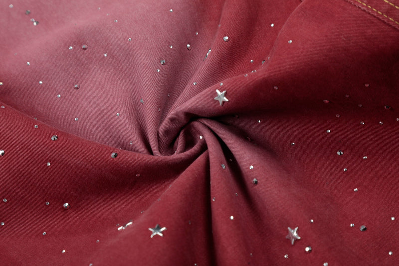 Close-up of red denim with rhinestone star splatter and gathered fabric folds