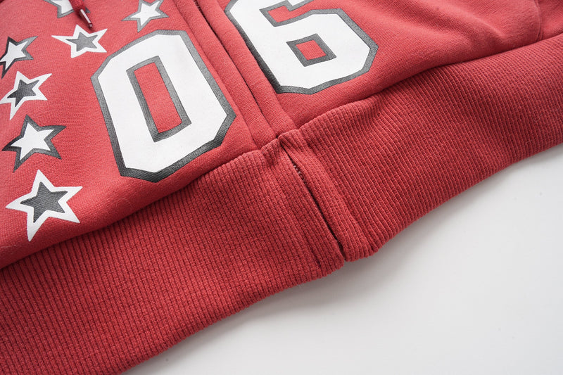 Front hem close-up of red hoodie with ribbed waistband and star graphic