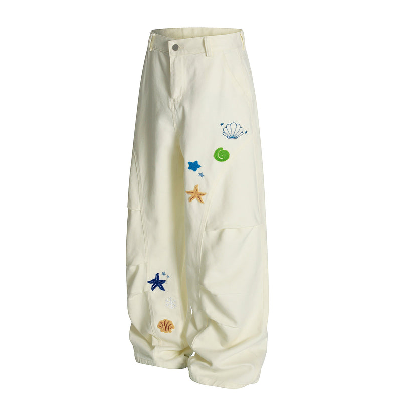 Cream wide-leg cargo pants shown at a slight angle with embroidered shell and starfish details