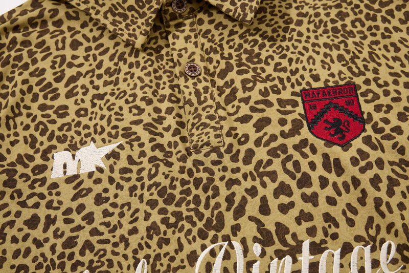 Close-up of a vintage leopard print polo tee with embroidered chest patches and button placket in Y2K streetwear style