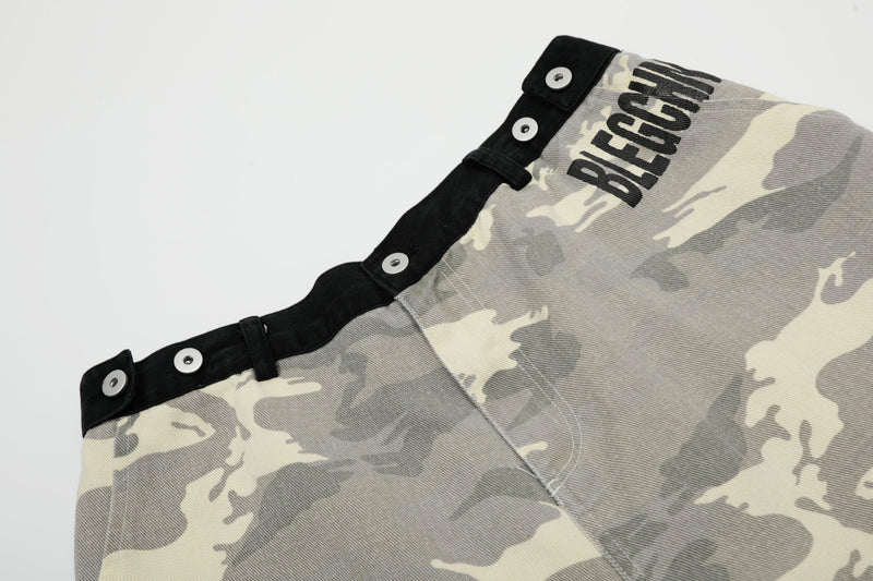 Close-up of upper side of gray camouflage shorts with black waistband and printed lettering