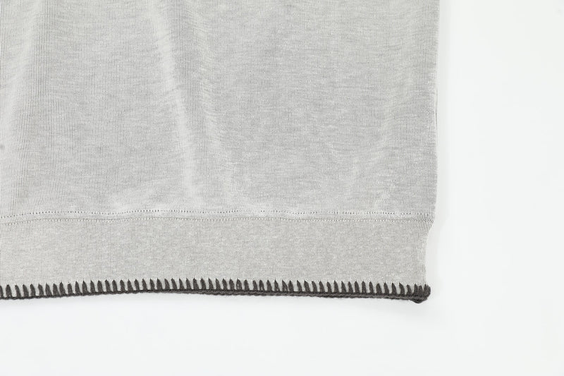 Light gray ribbed Henley tee hem with contrast stitch detail on a relaxed fit casual shirt