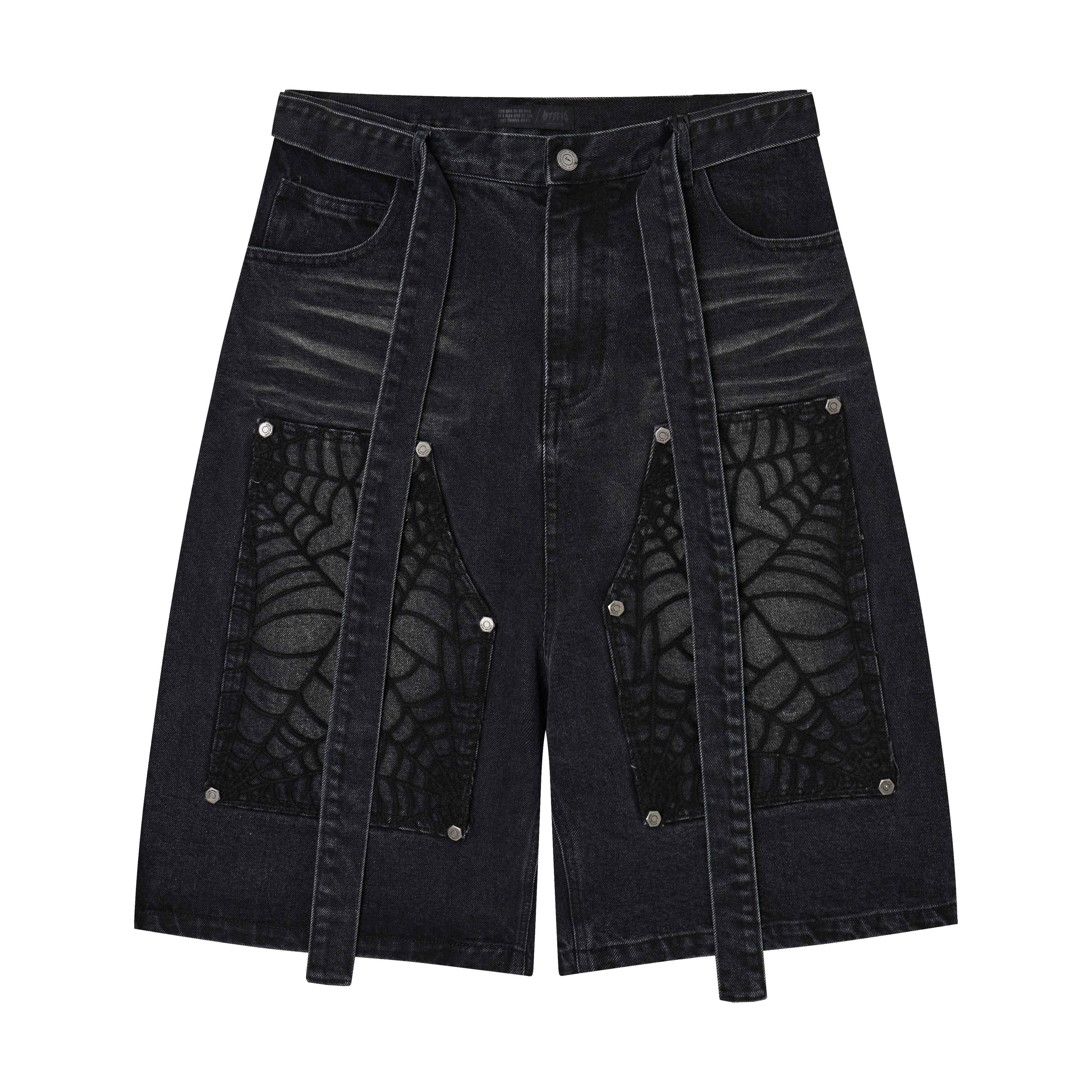 Front view of washed black denim shorts with spiderweb lace panel inserts, rivet accents, and extended strap detailing
