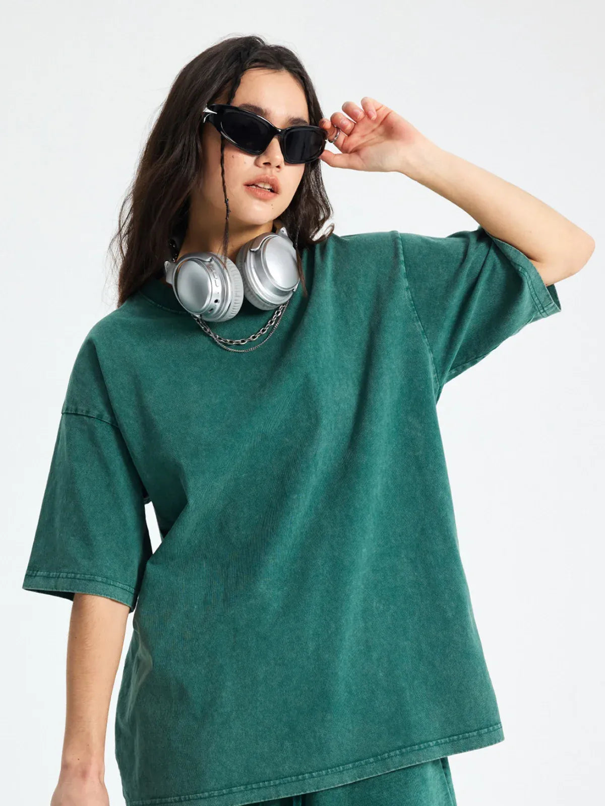 Wearing the Custom Anime Character Green Washed T-Shirt - Personalized Anime Style Tee, a person stands with one arm raised, accessorized with black sunglasses and large headphones, all set against a plain background.