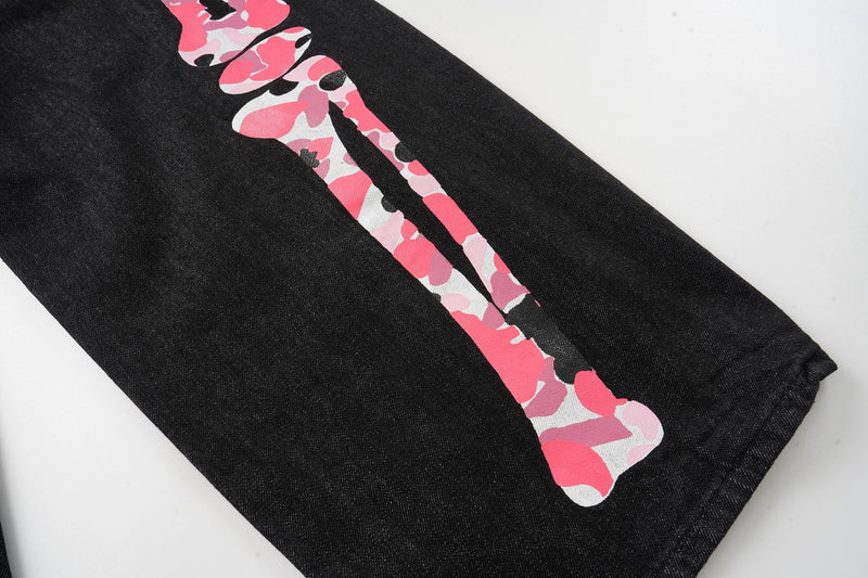 Pink camouflage skeleton print running down the leg of black denim pants