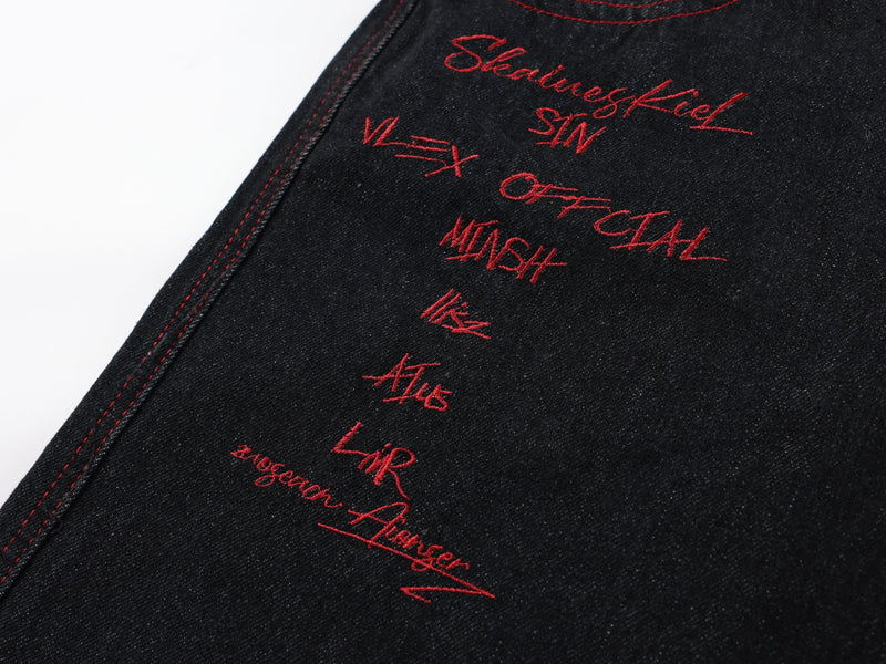 Close-up of red embroidered script on black denim pants