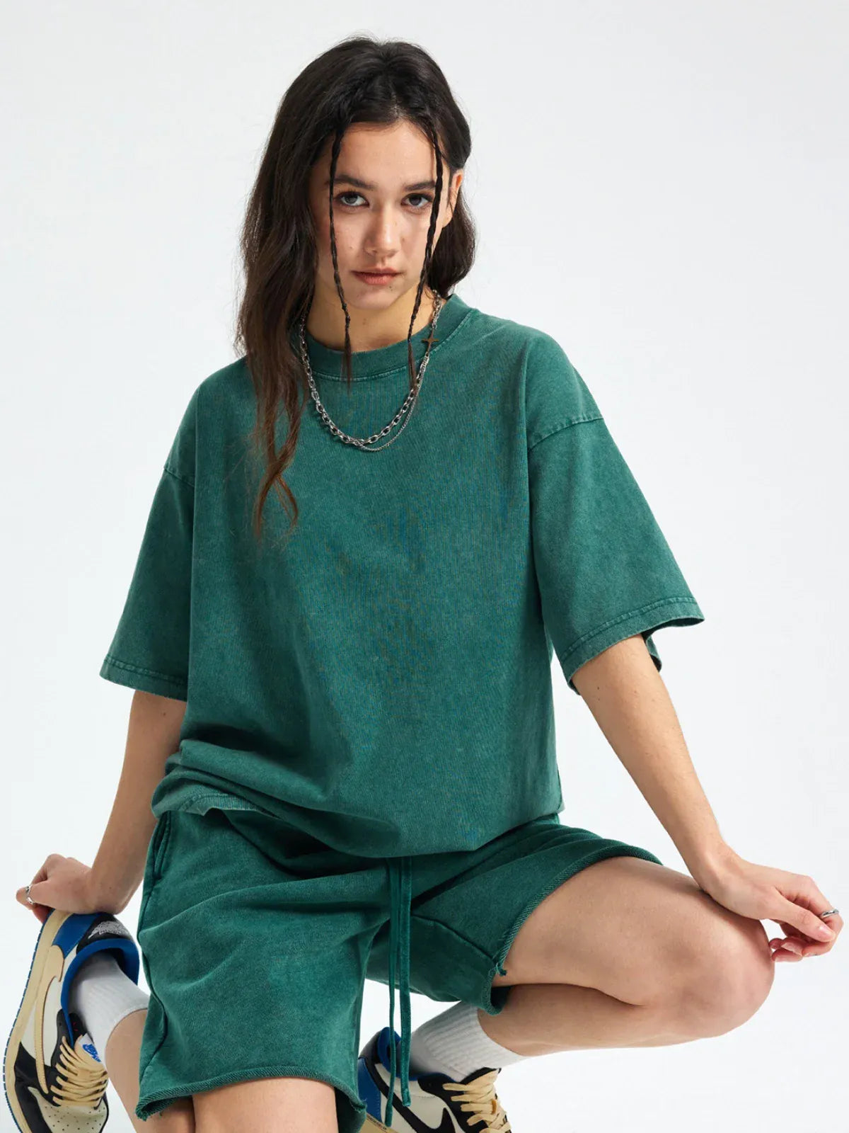 A person with long dark hair wears the Custom Anime Character Green Washed T-Shirt - Personalized Anime Style Tee and matching shorts, accessorized with layered chains, squatting against a plain white background.