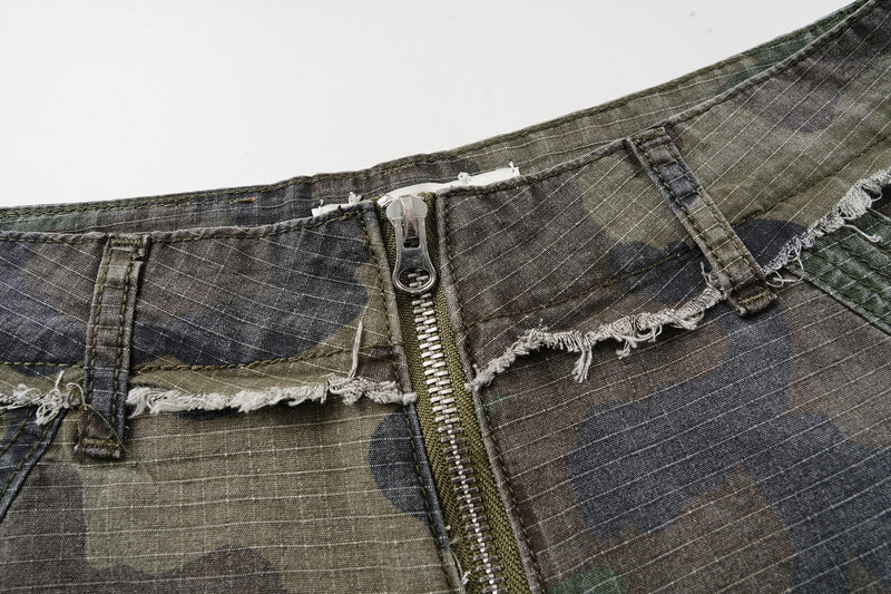 Close-up of the waistband and front zipper on camouflage cargo shorts with frayed trim