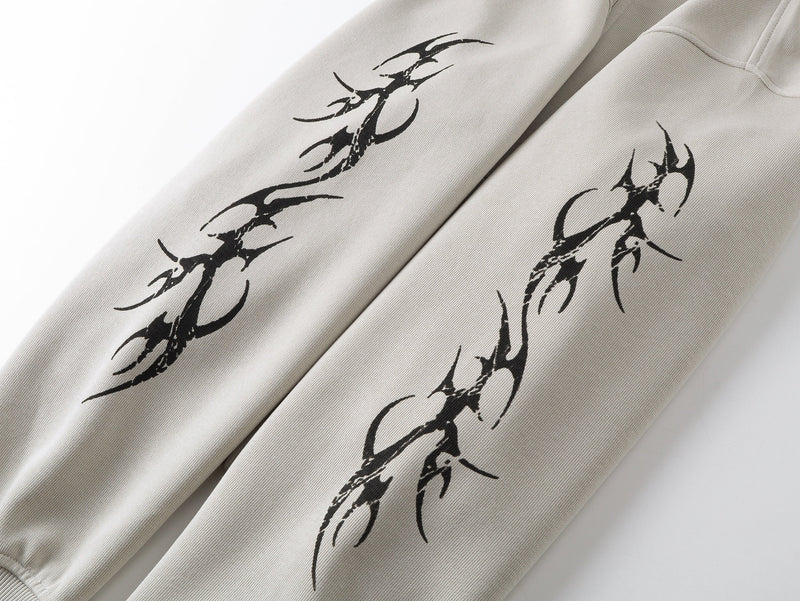 Close-up of beige hoodie sleeves with black tribal curve graphics