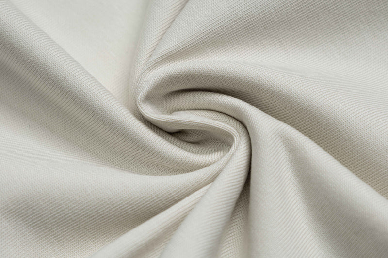 Close-up of soft beige cotton tee fabric with smooth woven texture and draped folds