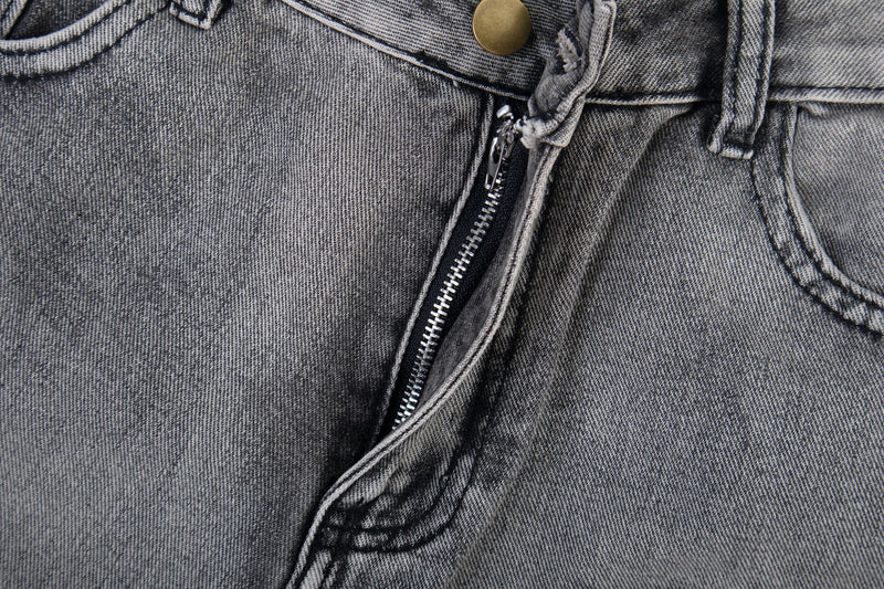 Close-up of front fly on grey wash jeans with zipper and button waistband detail
