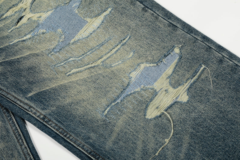Close-up of heavy frayed distressing across the upper leg of blue denim jeans