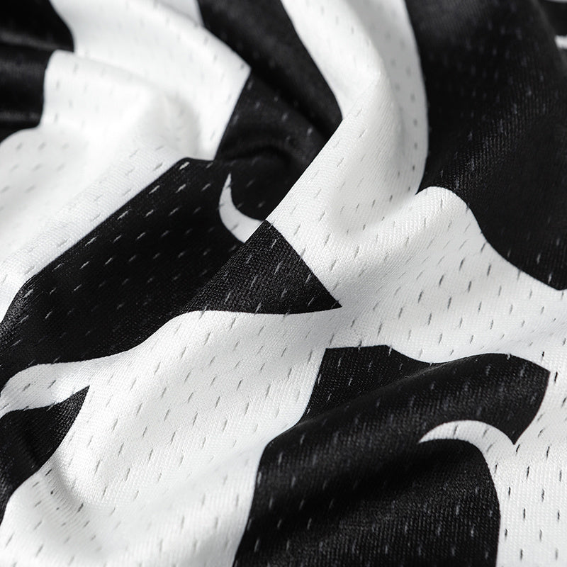 Close-up of black and white mesh jersey fabric with bold gothic-style graphics and breathable perforated texture