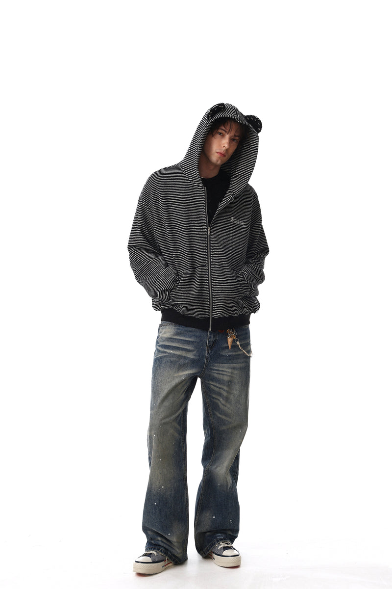 Model wearing black striped zip hoodie over jeans with hands in pockets