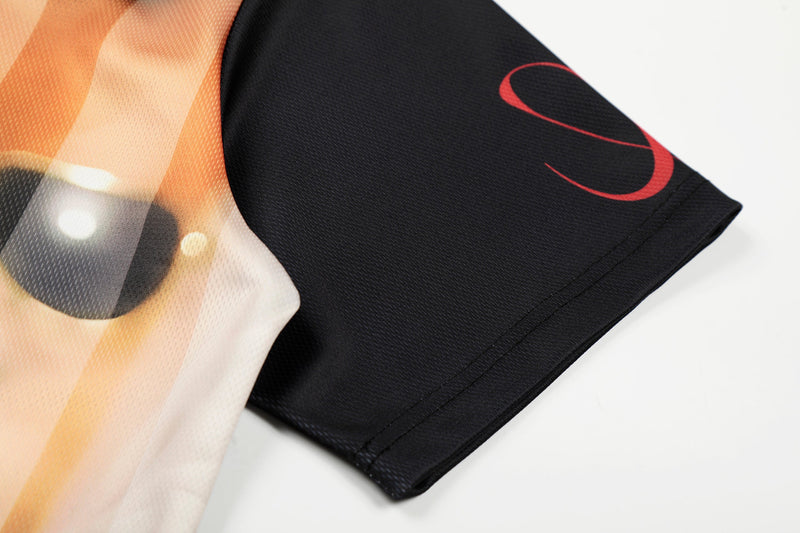 Close-up of an abstract portrait mesh jersey sleeve in black with orange and red graphic details on white background