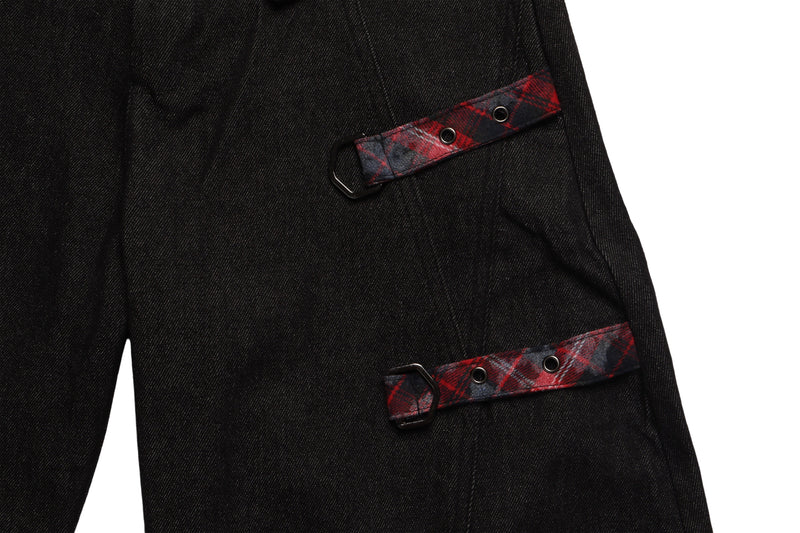 Close-up of black denim pocket flaps with red plaid strap and metal ring details