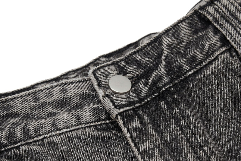 Close-up of denim waistband with silver snap button and faded black wash