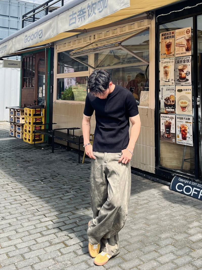 Model wearing light-washed olive wide-leg jeans with curved front seam detail and black T-shirt