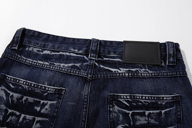 Close-up of the back waistband on deep indigo jeans with belt loops and black logo patch