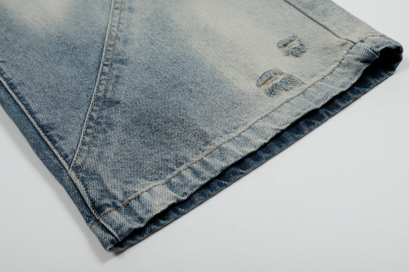 Folded hem of light and dark bleached denim shorts with small distress holes