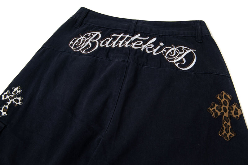 Back waistband close-up showing embroidered script on black cargo pants