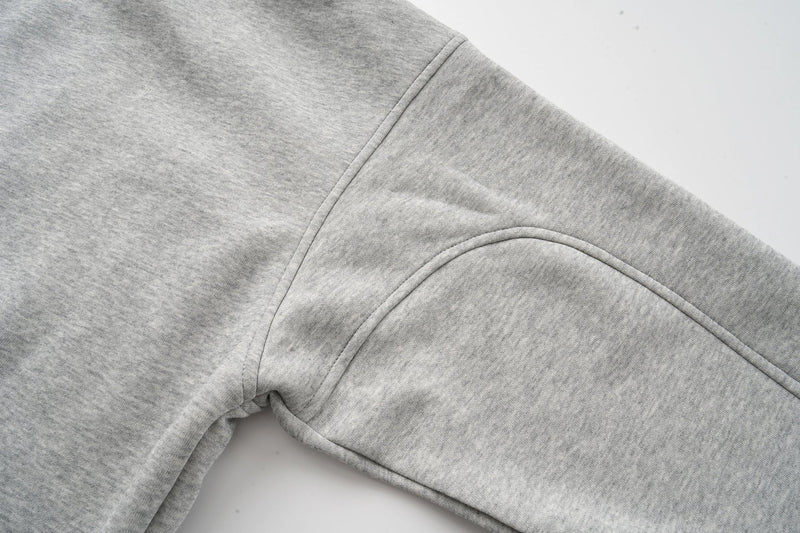 Side seam close-up of heather grey hoodie sleeve and shoulder panel stitching