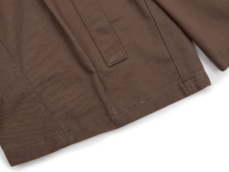 Close-up of brown shorts hem with stitched seam and side panel