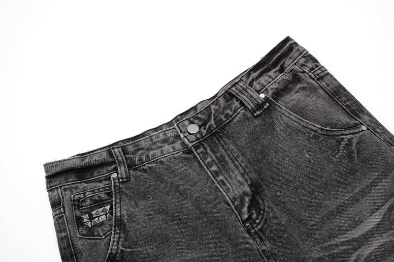 Top front close-up of distressed jeans showing belt loops, button, and studded pocket