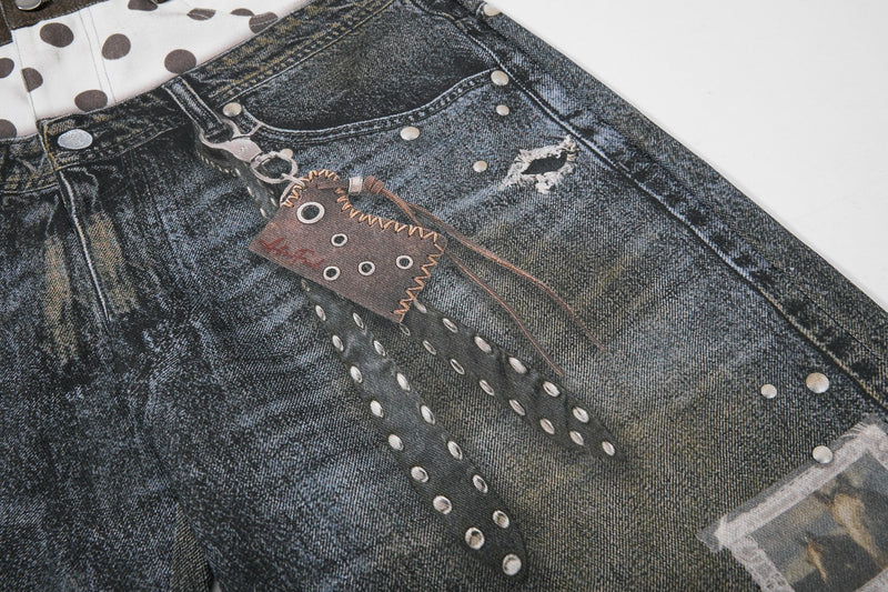 Close-up of printed denim leg with pocket graphic, stud details, and distressed patch