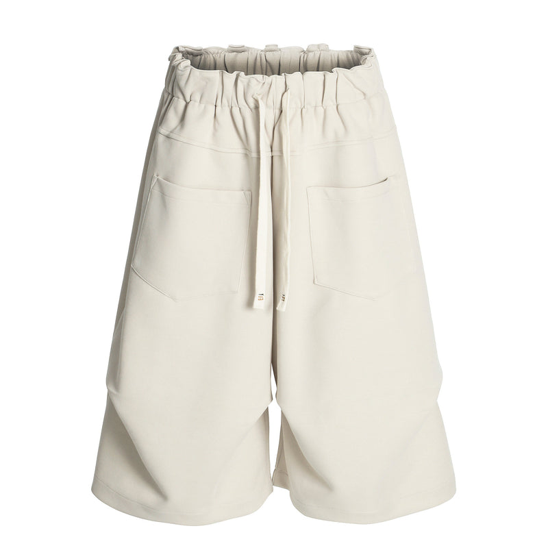 Cream wide-leg shorts front view with elastic waist, drawstring, and large patch pockets