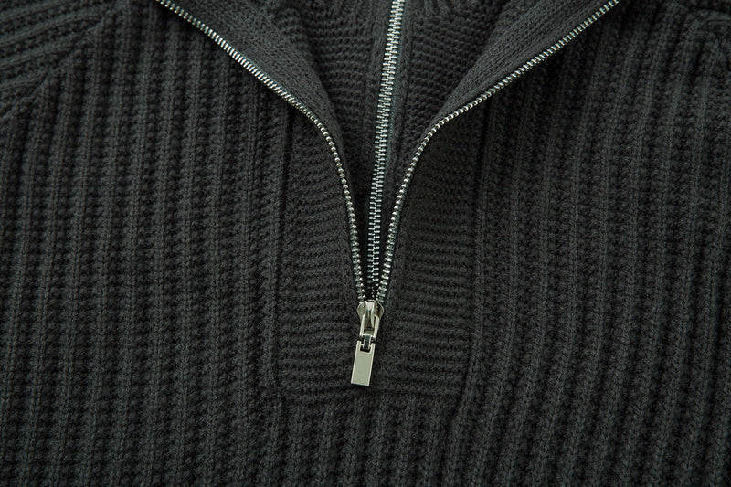 Close-up of black ribbed knit sweater chest with half-zip zipper detail