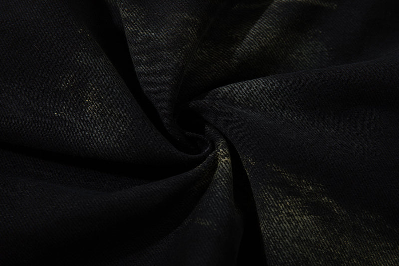 Close-up of black denim fabric showing texture and paint-wash fading