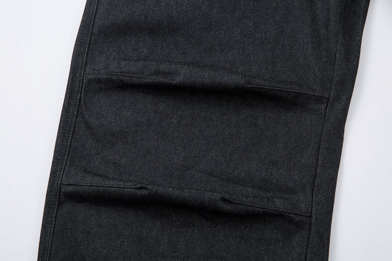 Close-up of one pant leg showing a horizontal pleat seam and dark denim texture