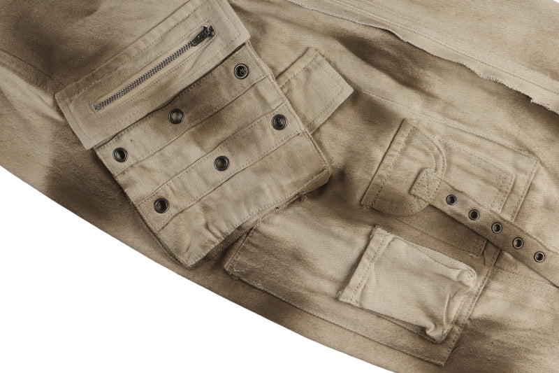 Close-up of cargo pocket details on beige pants with zipper trim, snaps, and flap closure