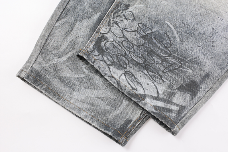 Close-up of hem and side seam on gray graffiti washed wide-leg denim pants