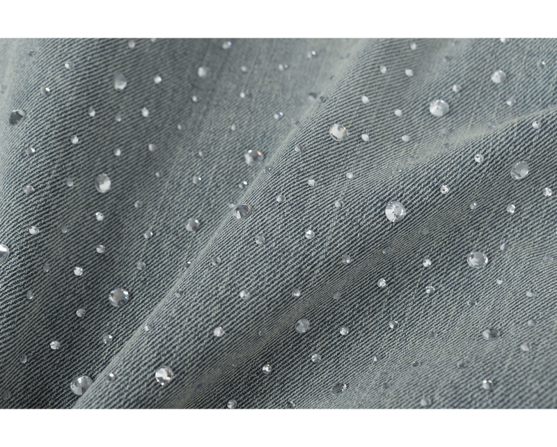 Close-up of light-wash denim with scattered clear rhinestones