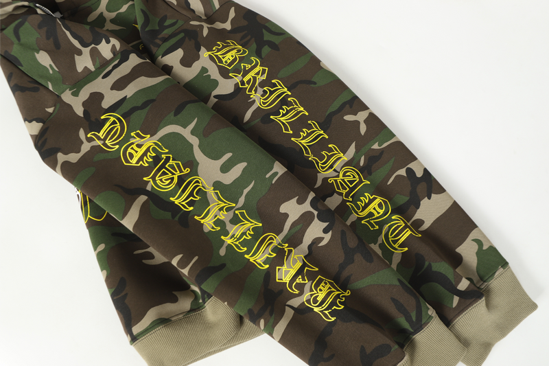 Sleeve view of camo hoodie with yellow gothic text print and ribbed cuffs