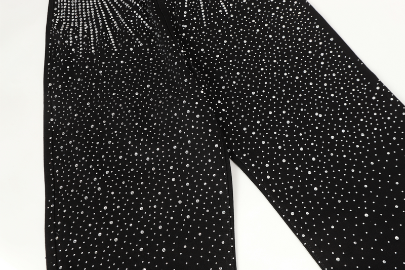 Black wide-leg jeans legs covered in scattered rhinestones