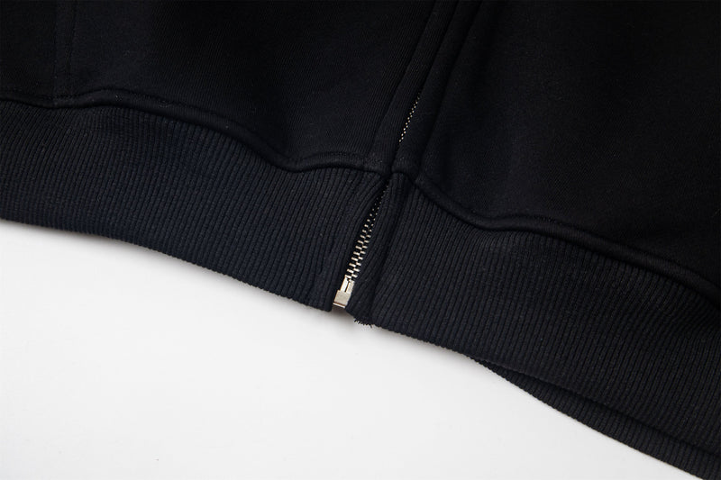 Bottom hem of black zip-up hoodie with ribbed trim and zipper