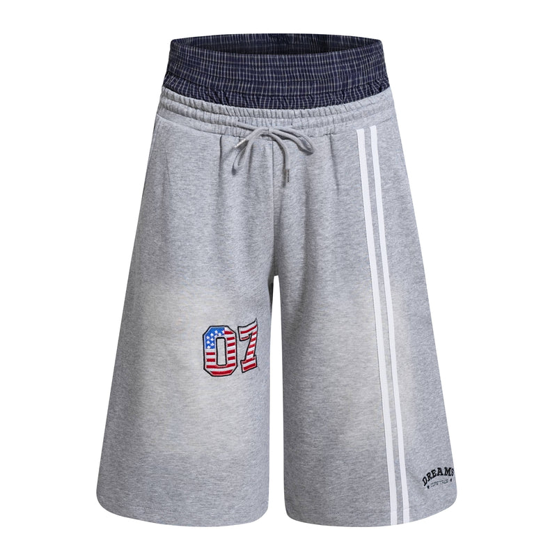 Light gray athletic shorts with navy plaid double waistband, white side stripes, and 07 patch