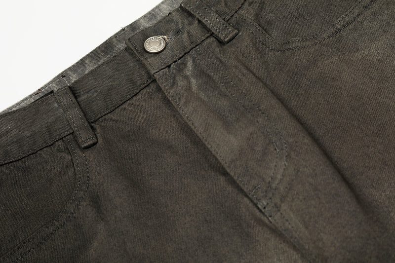 Close-up of front waistband and pocket on faded black denim pants with metal button