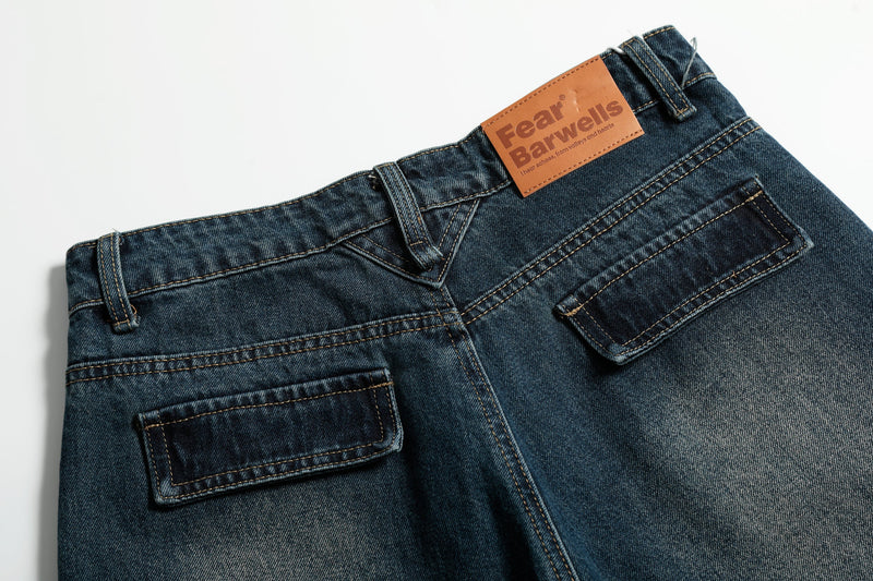 Close-up of back waistband on dark blue jeans with tan logo patch and rear pocket
