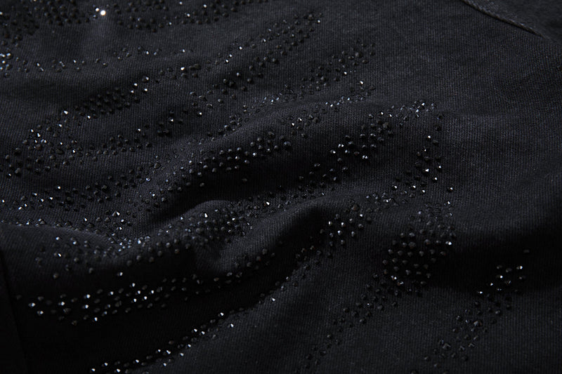 Close-up of black denim with scattered rhinestone swirl embellishments