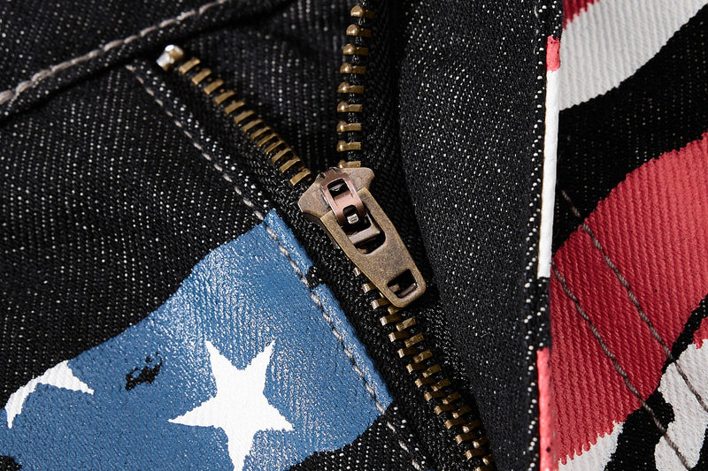 Close-up of zipper fly and printed denim panels on black jeans