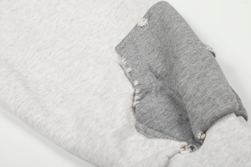 Close-up of white sleeve cuff with distressed holes and soft fleece fabric
