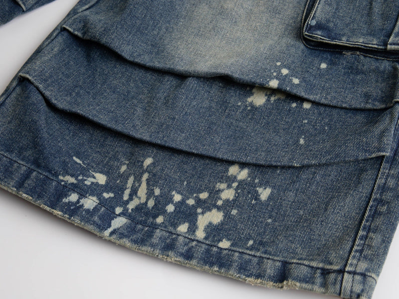 Close-up of lower leg hem with bleach splatter on blue denim shorts