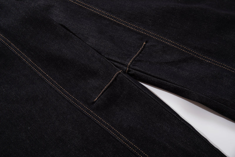 Close-up of dark wash denim crossing seams and stitched detail at the leg