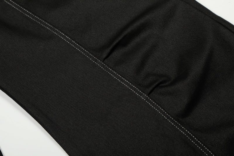 Close-up of a leg panel on black denim pants with a long contrast stitch seam
