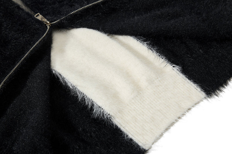 Close-up of white cross patch and zipper on black fuzzy hoodie