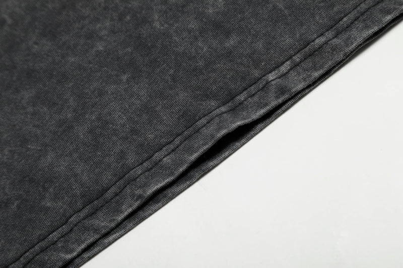 Close-up of black washed cotton T-shirt hem with visible stitching and soft faded texture